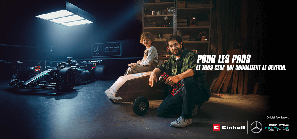 Un père et un enfant dans un atelier avec une caisse à savon faite maison. En arrière-plan, une voiture de Formule 1 Mercedes-AMG PETRONAS et des outils Einhell. À droite, il est écrit : « Pour les professionnels et ceux qui veulent le devenir. »