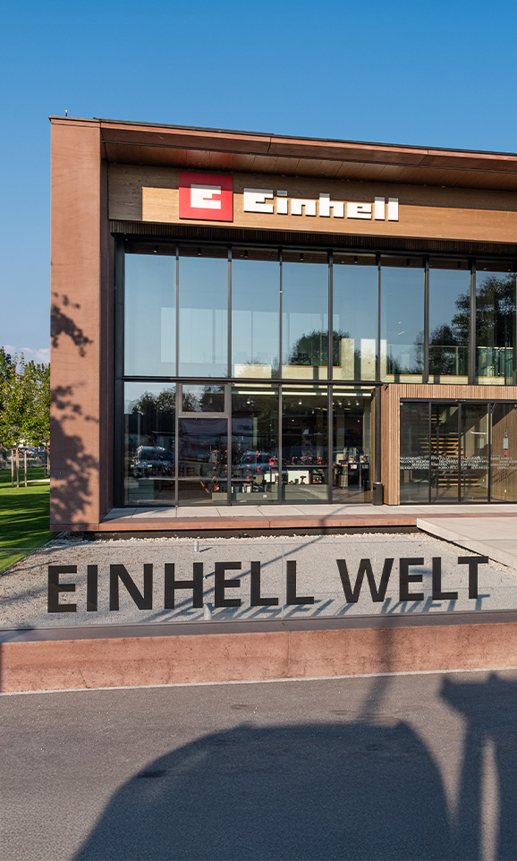 Einhell World : bâtiment moderne de l’entreprise avec le logo Einhell et un grand groupe de collaborateurs.