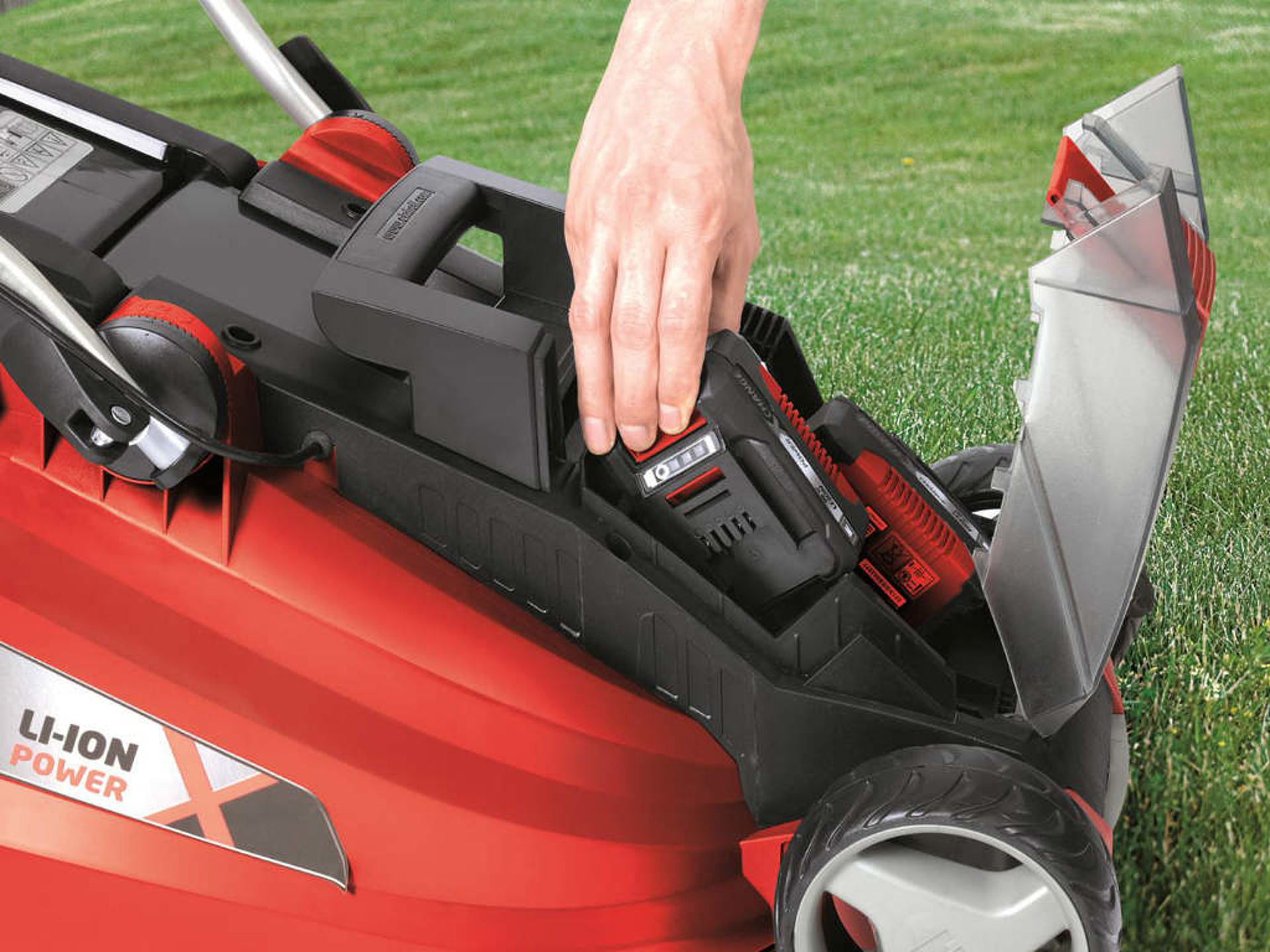 A man removes the battery from a lawn mower.