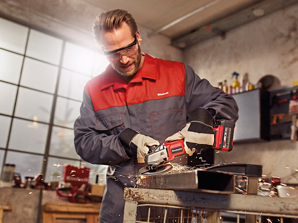 man working with cordless angle grinder in a workshop