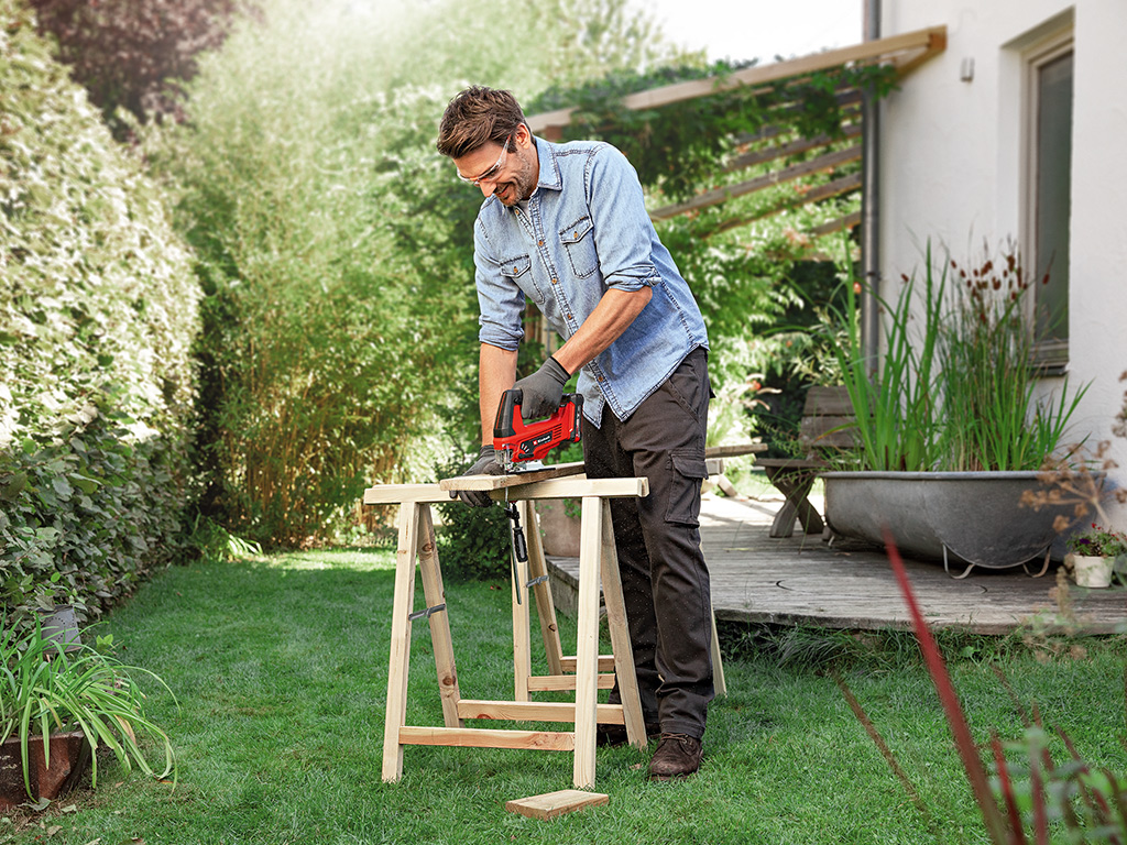 man working with cordless jigsaw in a garden