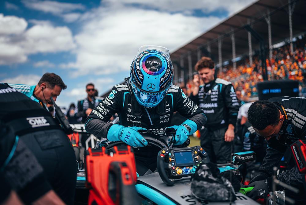 Formula 1 mechanics working on a race car in the pit lane.