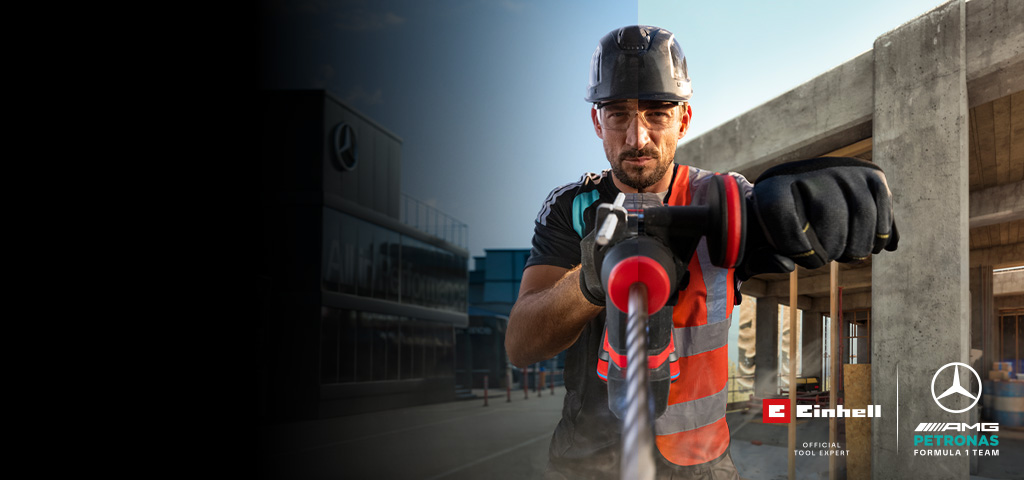 Un mécanicien en tenue de protection en train de percer à l'aide d'un outil électrique sur un chantier.