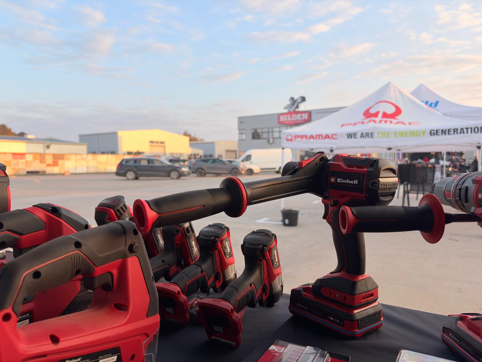 Einhell cordless tools displayed at an outdoor event with branded tents and buildings in the background