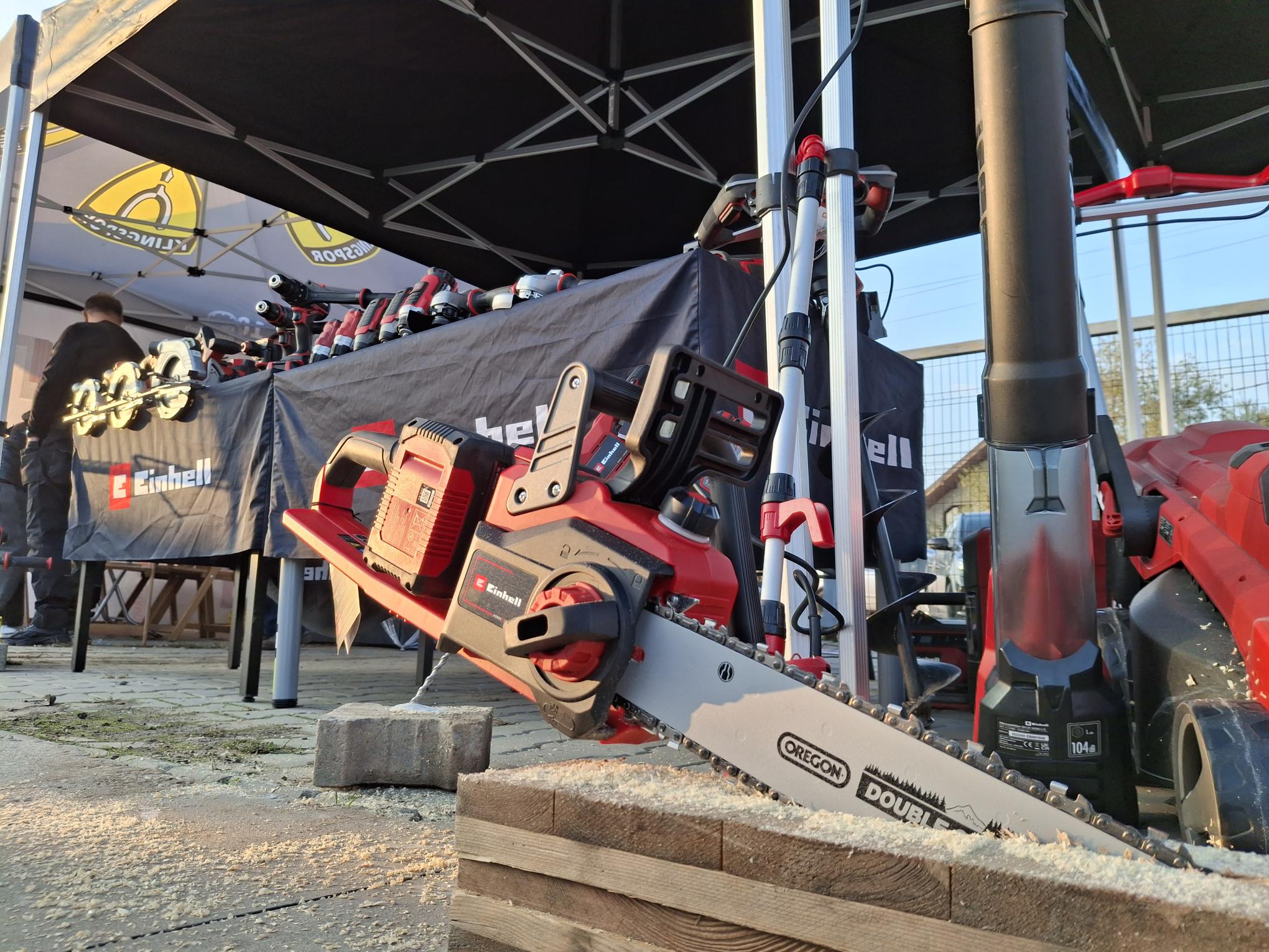 Einhell cordless chainsaw and garden tools displayed at an outdoor event stand