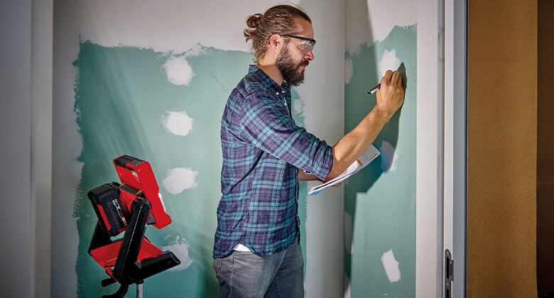 Man painting on wall next to a lamp