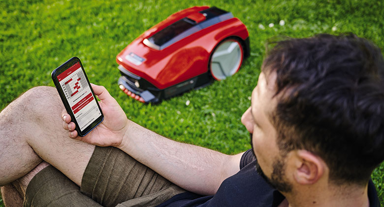 A man setting up his robotic lawn mower through an app. 