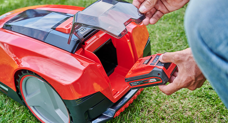 A man inserting a Power-X-Change battery into the robotic lawn mower. 